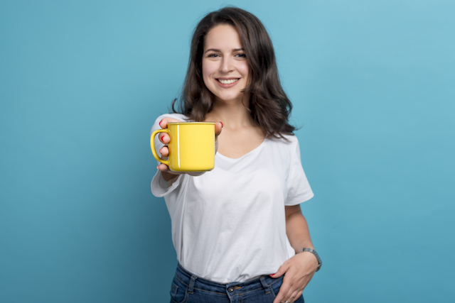 Girl smiling holding out cup of coffee.