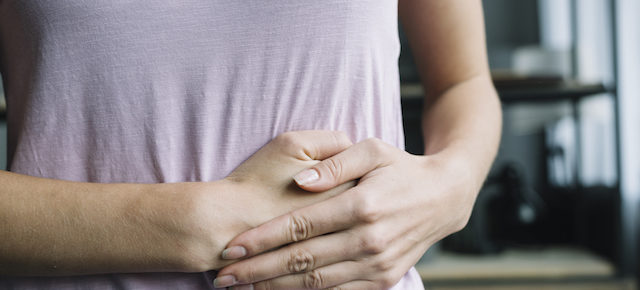 woman placing hand on abdomen for cramps.