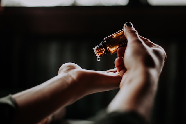 Woman pouring out essential oils onto hand. 