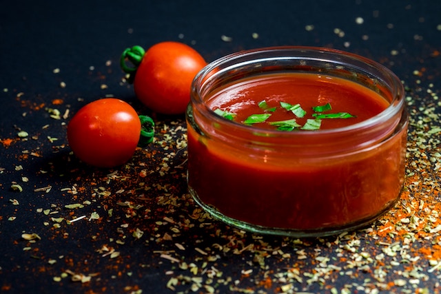 Bowl of fresh tomato sauce next to some tomatoes.