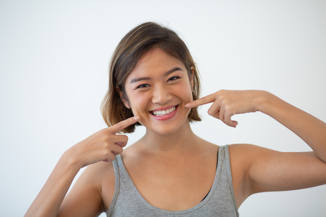 woman smiling and pointing to her teeth.