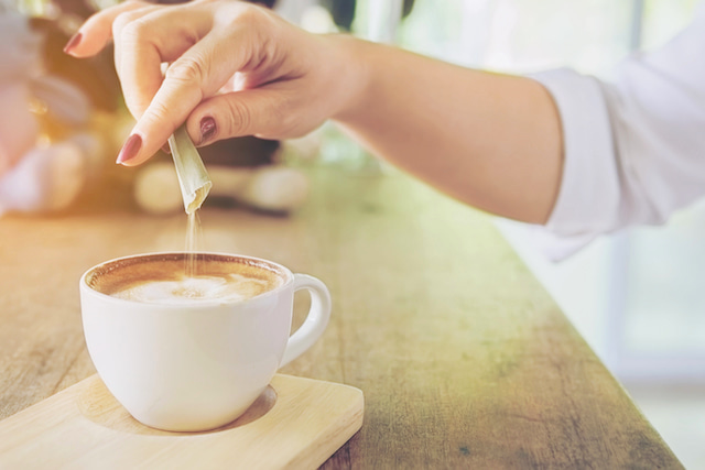 cup of coffee with sucralose substitute being added. 