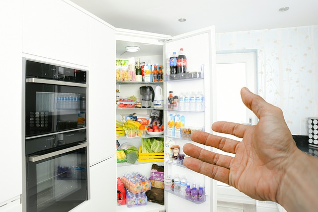 man with hand toward his fridge full of groceries.