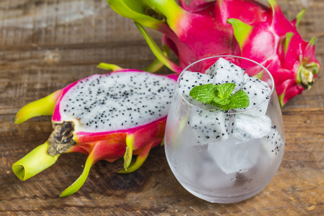 a cut dragon fruit and a drink with dragon fruit ice cubes.
