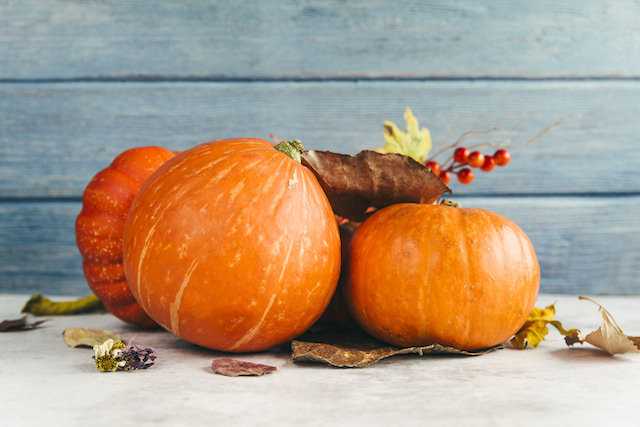 several pumpkins with some leaves that represent fall. 