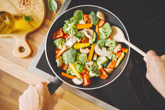 person cooking vegetablesin a pan on the stove. 