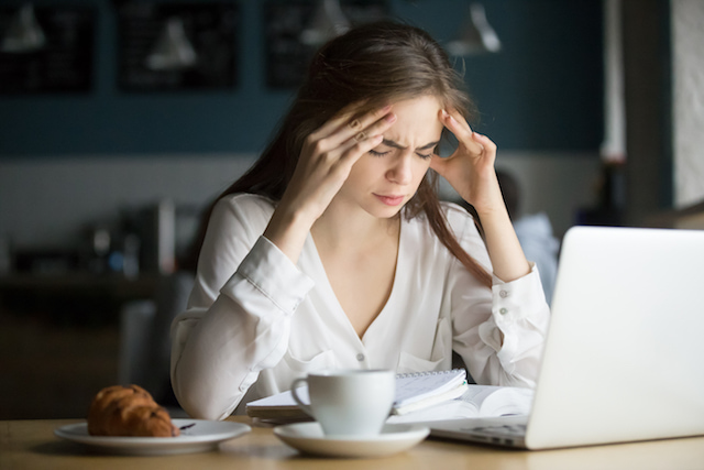 woman holding her forehead with a headache because she's stressed. 