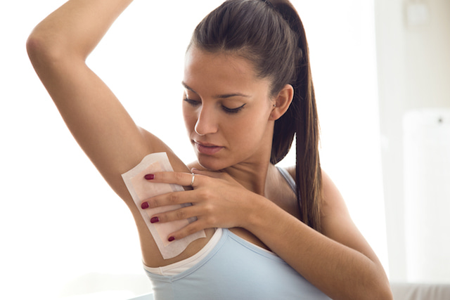 woman drying her armpit that is excessively sweating because she is stressed. 