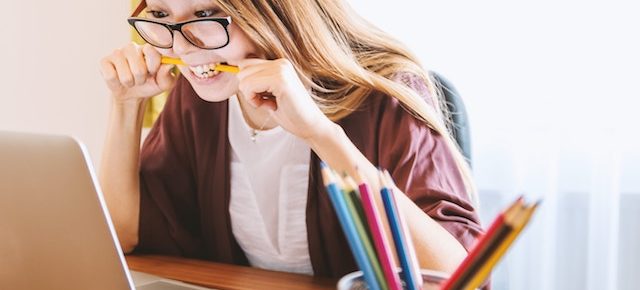 woman chewing a pencil to reduce stress.