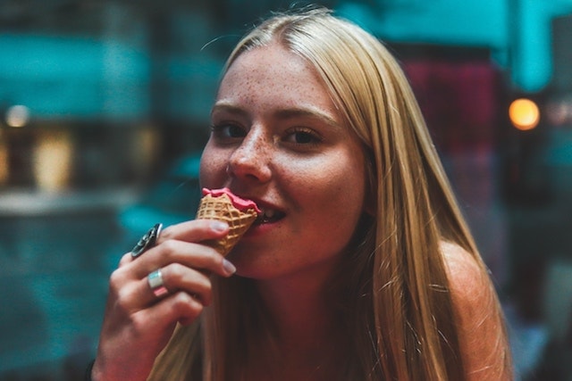 woman smiling while eating an ice cream cone at night. 